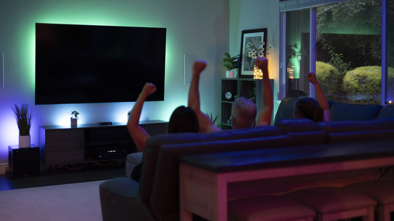 family cheering before the tv in the living room with special dim lights