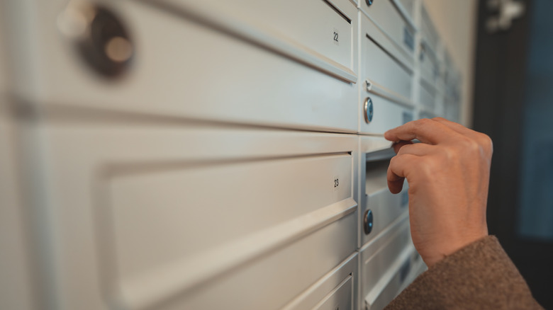 A person opening an apartment mailbox