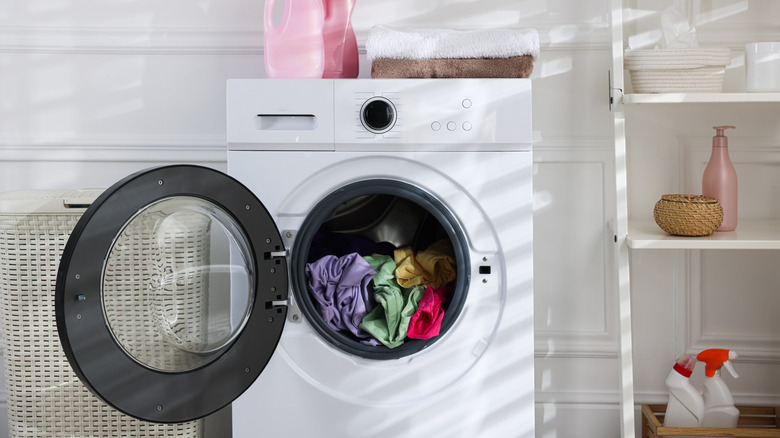 a washing machine loaded with clothes, door open