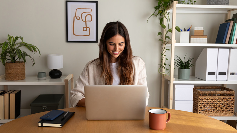 A woman working on a laptop in her home office.