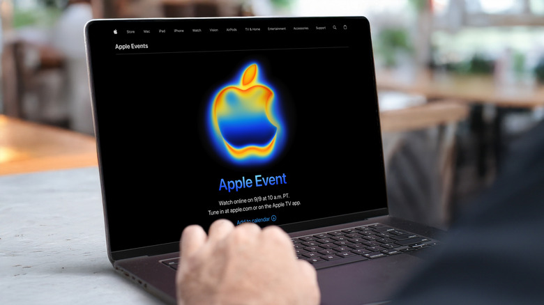 Businessman using a MacBook Pro laptop with the upcoming Apple Event 2025 announcement on screen