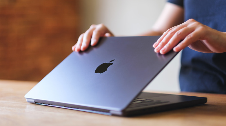 A woman opening or closing a MacBook Pro laptop
