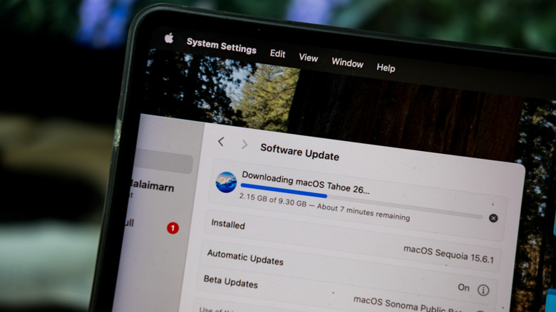 Installing Software update MacOS 26 Tahoe system on MacBook and Liquid Glass display features on a computer screen.