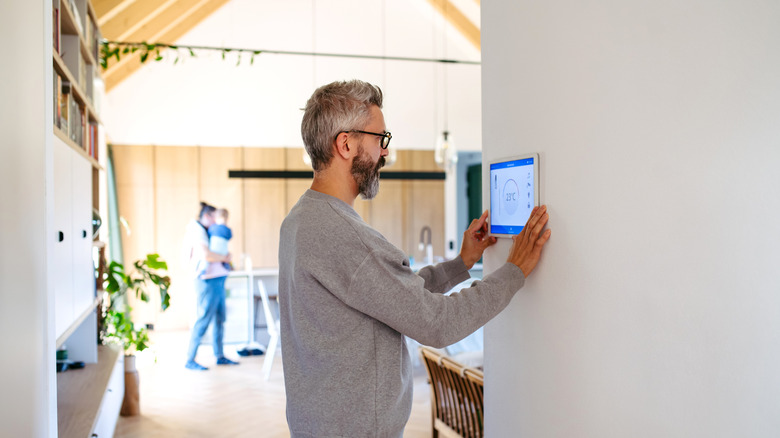 Man on his smart thermostat setting it up for his home
