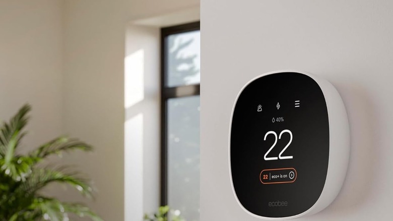 Ecobee Thermostat hanging on the side of a wall, displaying the current temperature