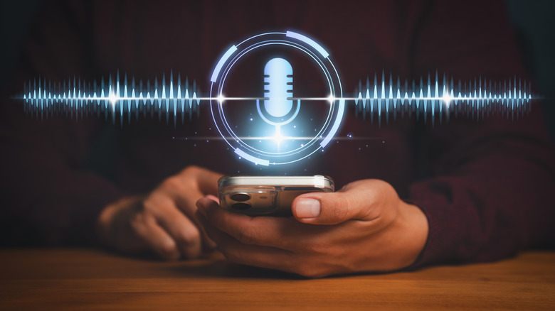 Smart phone in a person's hand with the microphone icon hovering above it