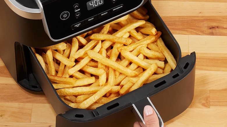Ninja Air Fryer tray being pulled out with a basket full of cooked fries