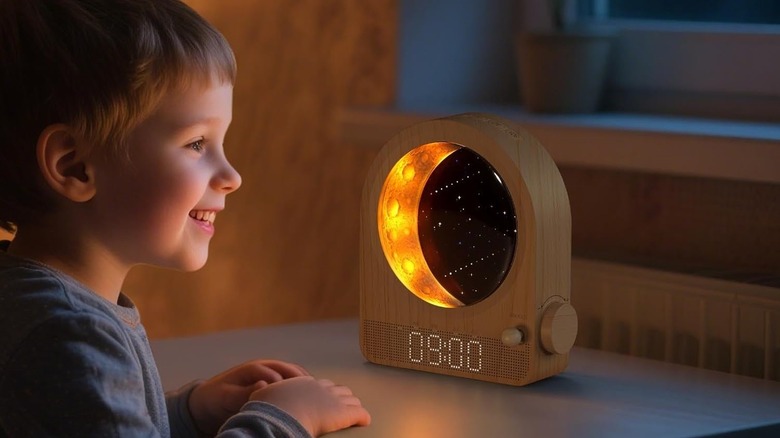 A child looking at the Epochleno Sunrise alarm clock on a desk.