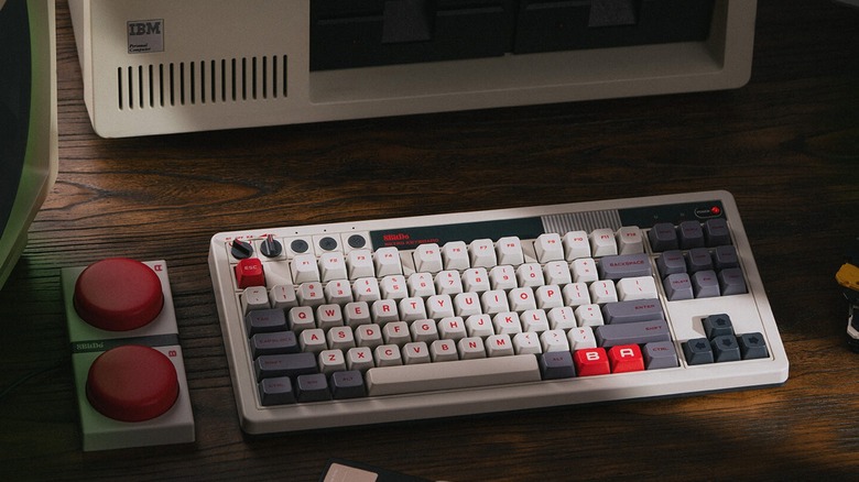 The 8BitDo Retro mechanical keyboard on a wooden desk surrounded by other retro tech