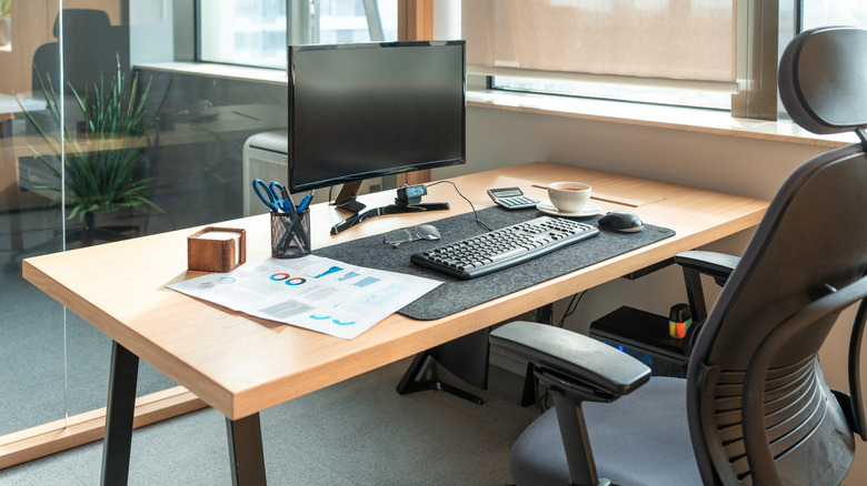 Desktop computer on a desk with keyboard and chair in view