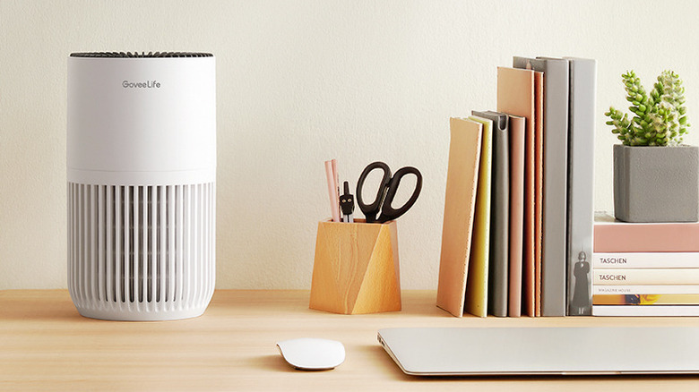 The GoveeLife H7126 smart air purifier on a desk, beside work items such as a mouse and laptop.