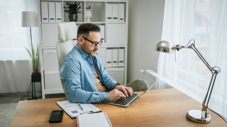 A man working on a laptop in a home office.