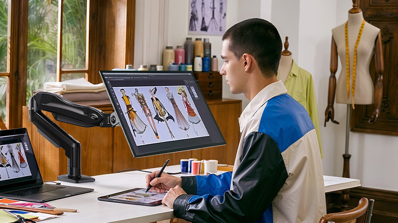 A person looking at a monitor that's attached to the Huanuo HNSS6 FlowLift single monitor mount.
