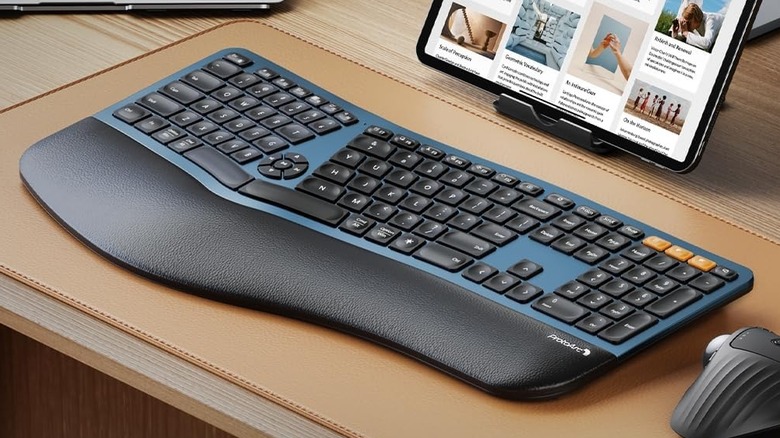 The ProtoArc EK01 Plus ergonomic keyboard in front of a tablet and beside a mouse.