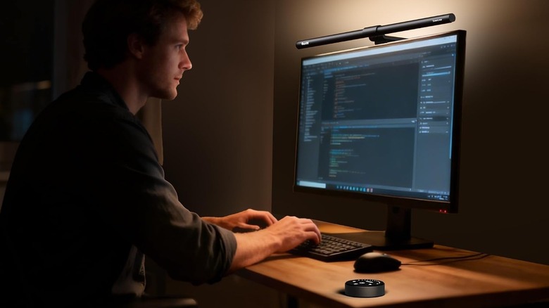 The Quntis ScreenLinear Glow monitor light bar installed on a monitor, with its control puck on a desk.