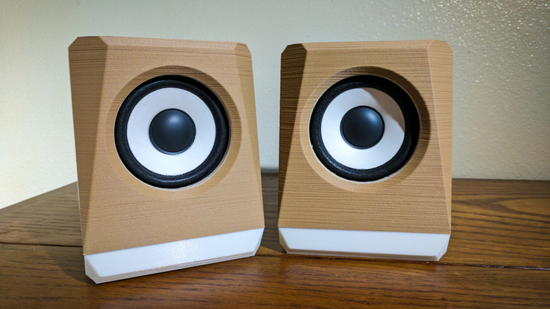 Two 3D printed speaker bodies on a wooden table.