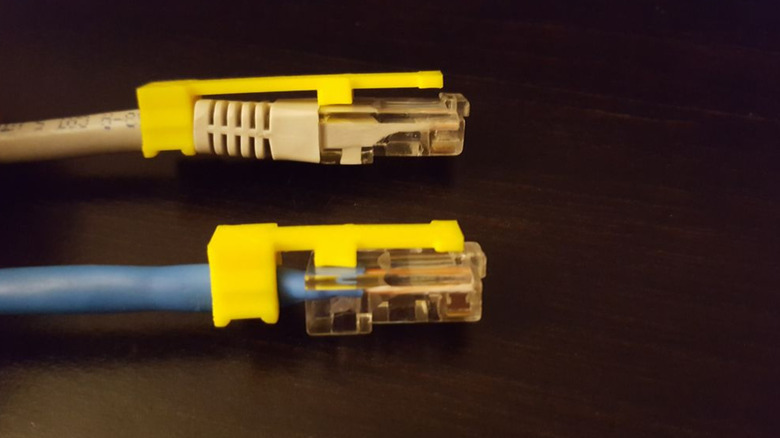 A close up of two ethernet cables with 3D printed replacement clips attached.