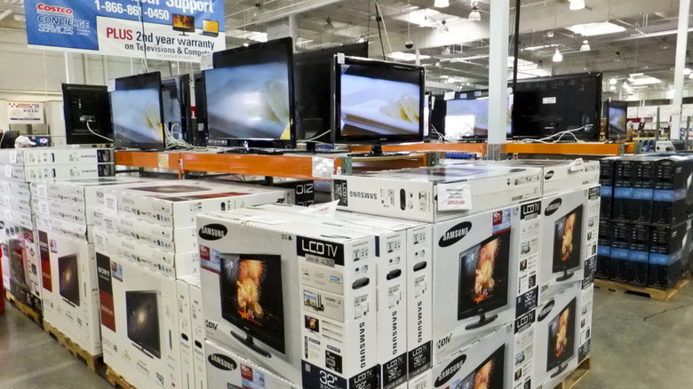 Costco electronics section with multiple TV monitors on, with large stacks of them on the show floor