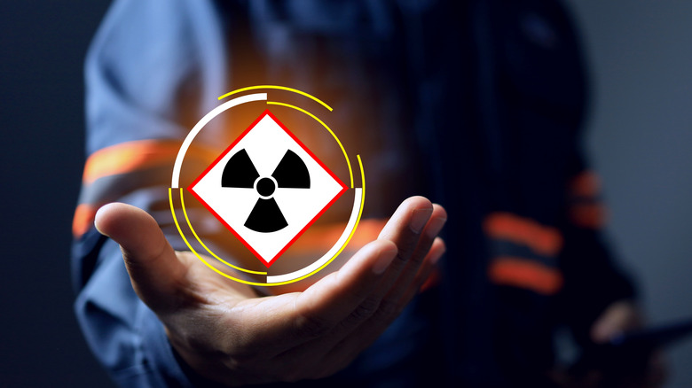 A person holding a glowing radiation hazard symbol.