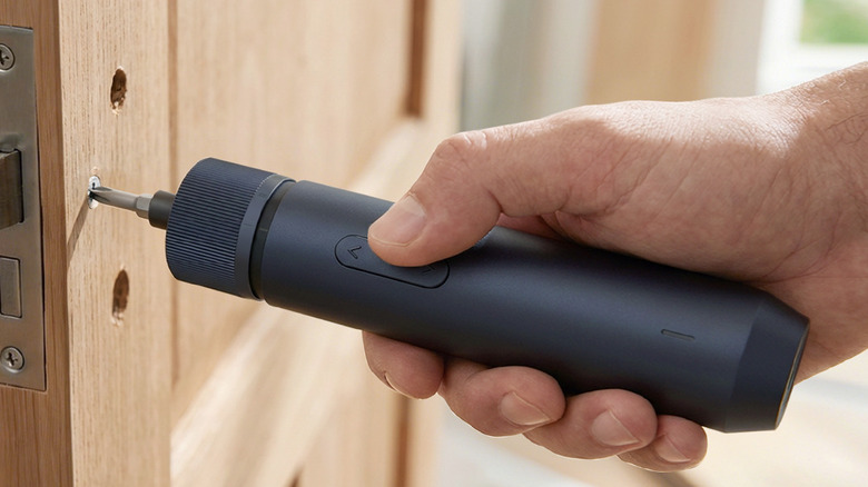 A person using the Hoto QWLSD011 electric screwdriver on a screw on a door.