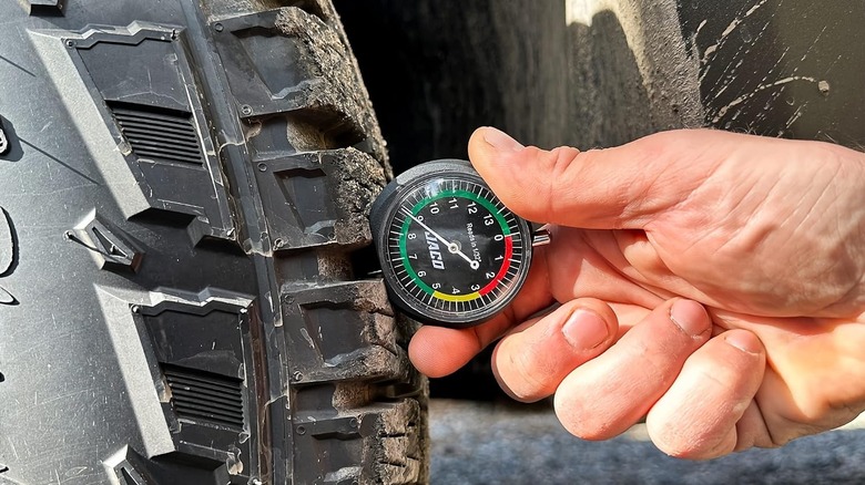 A person using the Jaco TreadPro tire tread depth gauge on a tire.