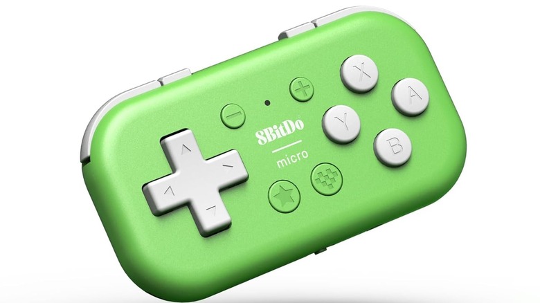 A small green 8BitDo Micro wireless game controller with gray buttons and directional pad, shown floating against a white background.