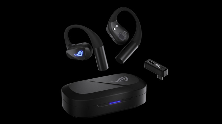 Black gaming earbuds with ear hooks floating above a matching charging case, alongside a small USB-C wireless dongle on a black background.