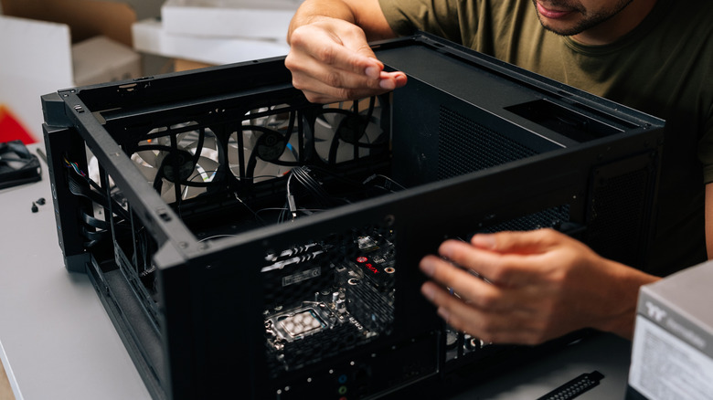 A person working inside of a PC case, seemingly performing repairs.