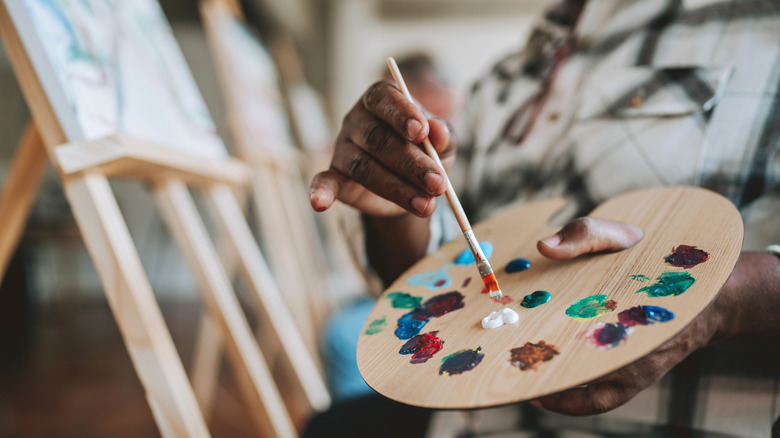 A painter holds a color palette while in the process of painting.