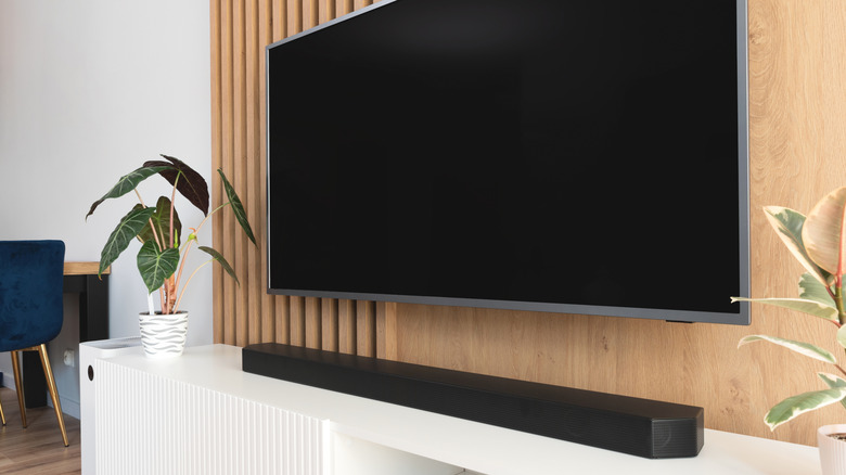 A TV with a large soundbar on a stand below it.