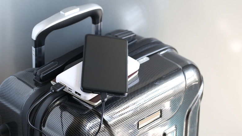 A power bank connected to a phone, placed on top of a suitcase