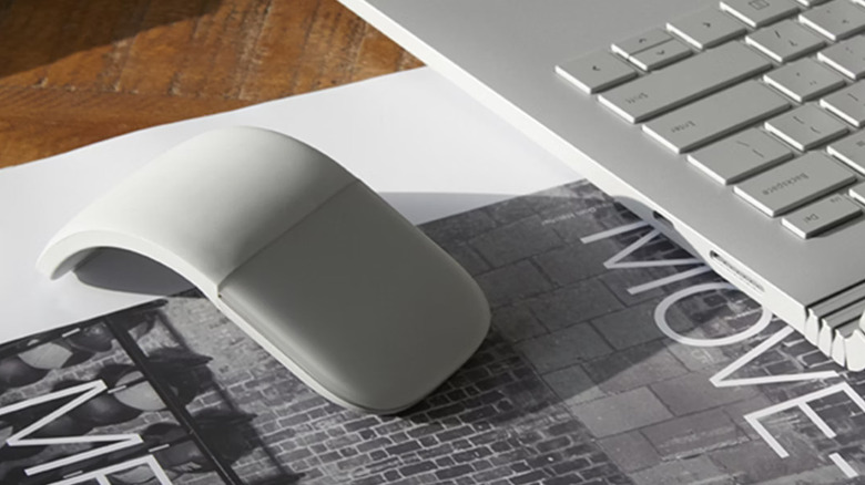 The Microsoft Surface Arc Mouse next to a laptop