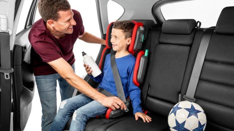 Parent securing child in mifold chair in car