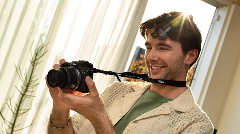 Man using Canon EOS R111 mirrorless camera in living room