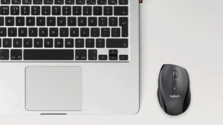 The Logitech M705 Marathon wireless mouse on a gray surface, beside a laptop.