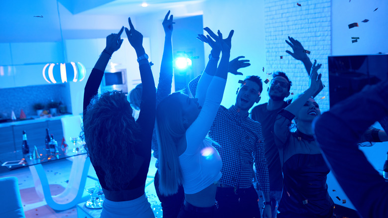 A group of people at a house party with blue light behind them.
