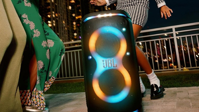 People dancing around the JBL PartyBox Stage 320 portable speaker.