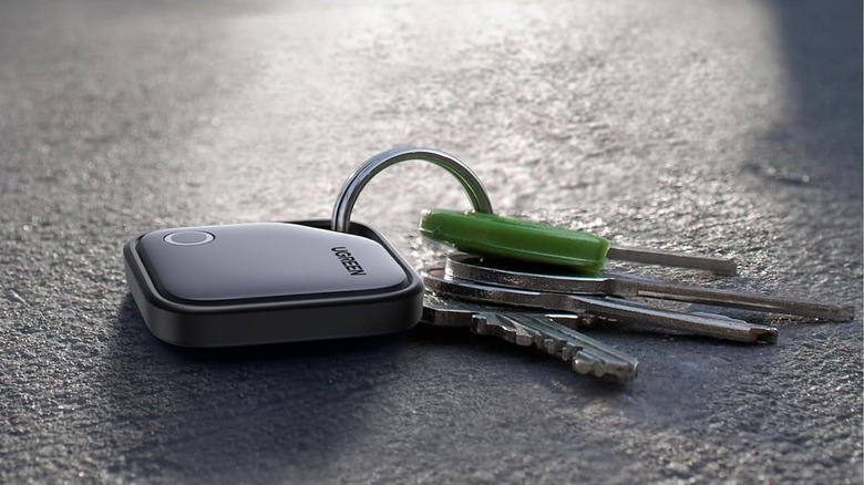 The UGREEN FineTrack tracker tag on a keychain, on the ground.