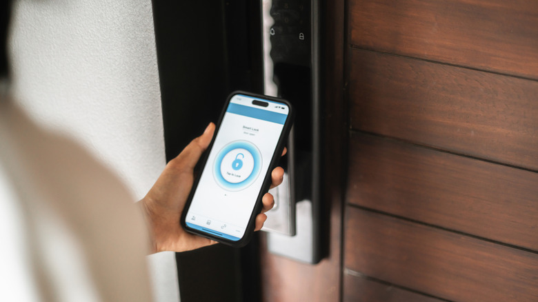 Close-up of a hand holding a smartphone to unlock a smart door lock