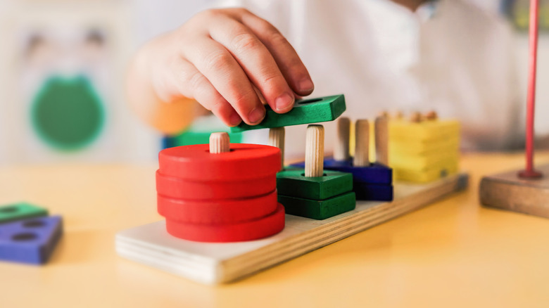 A hand playing with wooden blocks on a table.