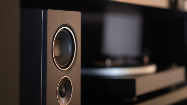 A large speaker with a blurred turntable in the background