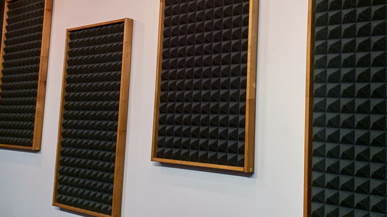 Wall-mounted acoustic foam panels with pyramid-shaped sound-absorbing surfaces, installed in wooden frames to reduce echo and improve room acoustics.