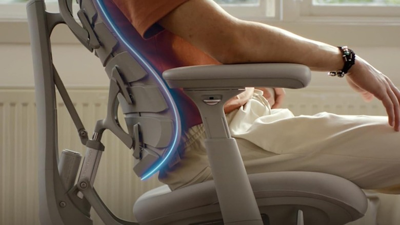 Side view of a person sitting in an ergonomic office chair with a flexible backrest designed to support the natural curve of the spine and promote healthy posture.