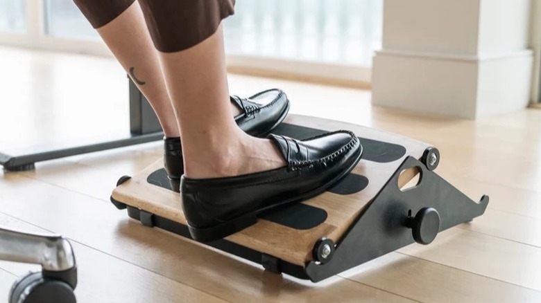 A person resting their feet on the Humanscale FR 300 Footrest.