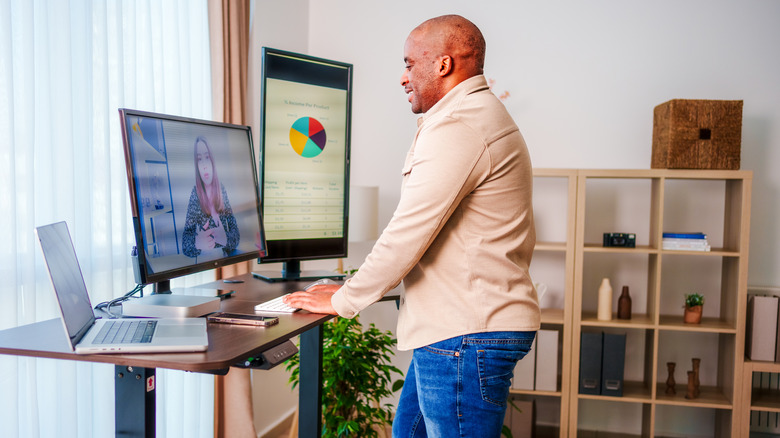 A man using a standing desk while engaged in a video call.