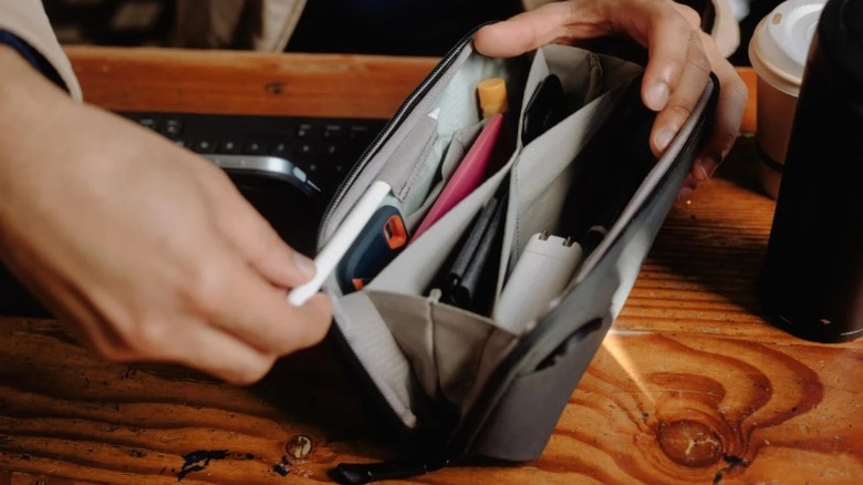 A person examing a Peak Design Tech Pouch loaded with accessories.