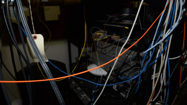A big tangled mess of cables in a dimly-lit server room