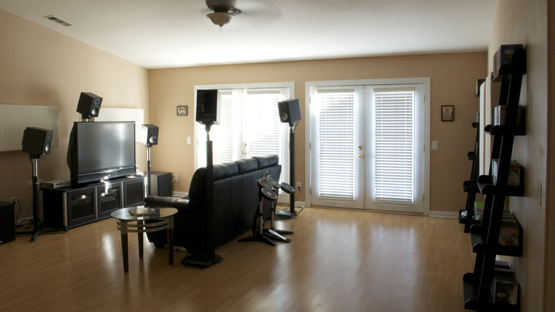 Home theater setup with speakers too high, no acoustic treatment, and sunlight shining on the TV