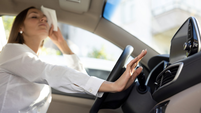A woman sweats in her, holding her hand out to the A/C vent