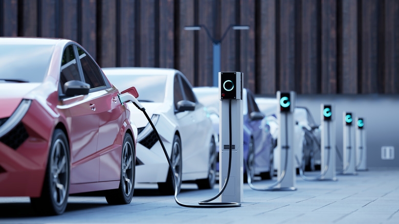 A row of generic electric cars on a street, charging
